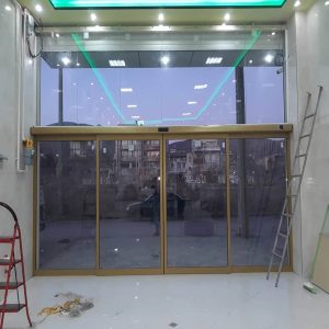 درب اتوماتیک شیشه ای با فریم آلومینیومی در ورودی مدرن